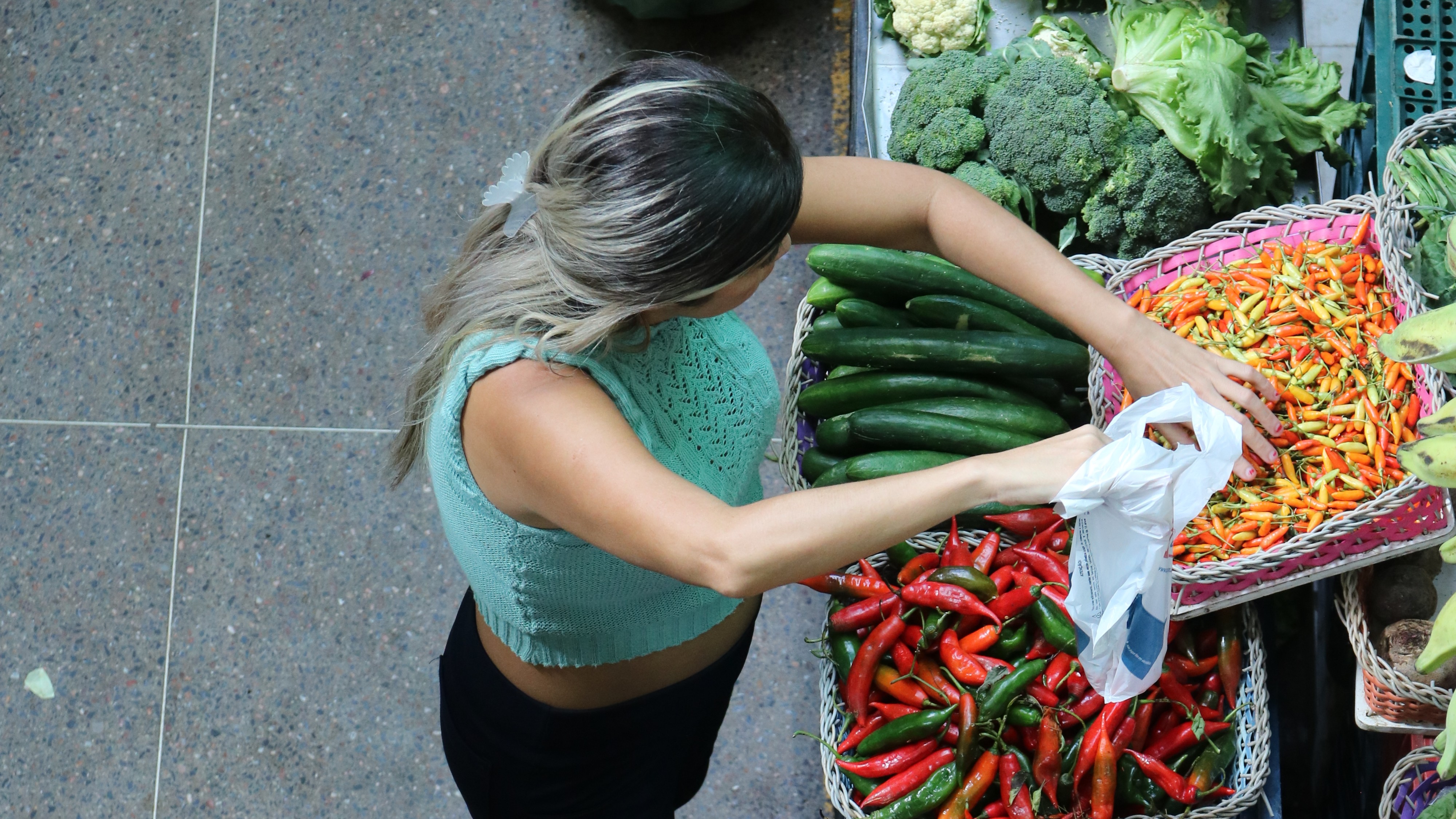 mulher escolhendo verduras em uma banca de mercado